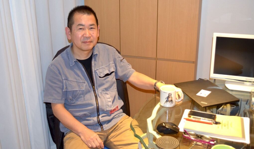 Yu Suzuki sitting on his desk