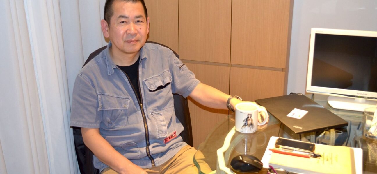 Yu Suzuki sitting on his desk